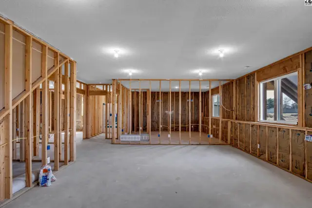 Unfinished basement with exposed wood framing, concrete floor, and a single window.