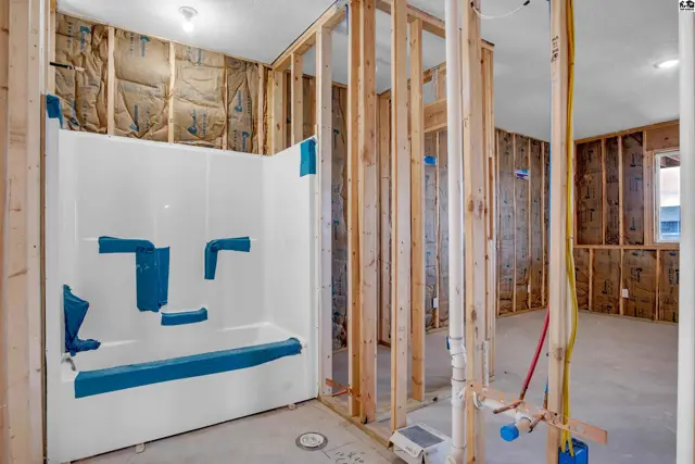 Unfinished bathroom with a white tub/shower unit and exposed wood framing.