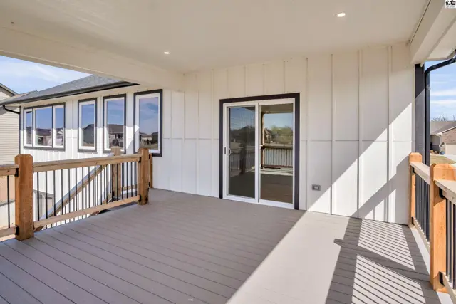 Spacious covered deck with wood railings and modern gray composite decking, overlooking a backyard.