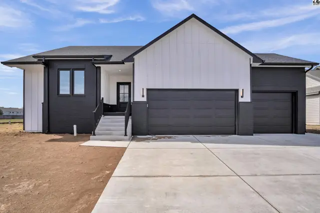 Modern home exterior with black and white siding, a large garage, and a welcoming entryway.