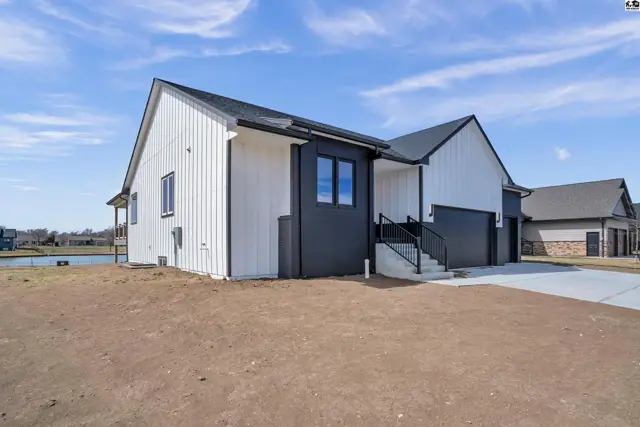 Modern white and dark gray exterior with black trim, a garage, and a pond view.