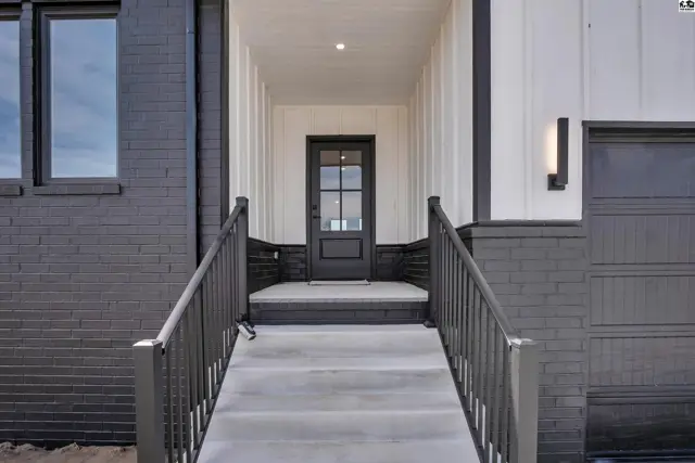 Modern entryway with black brick, white vertical siding, and a glass-paneled front door.