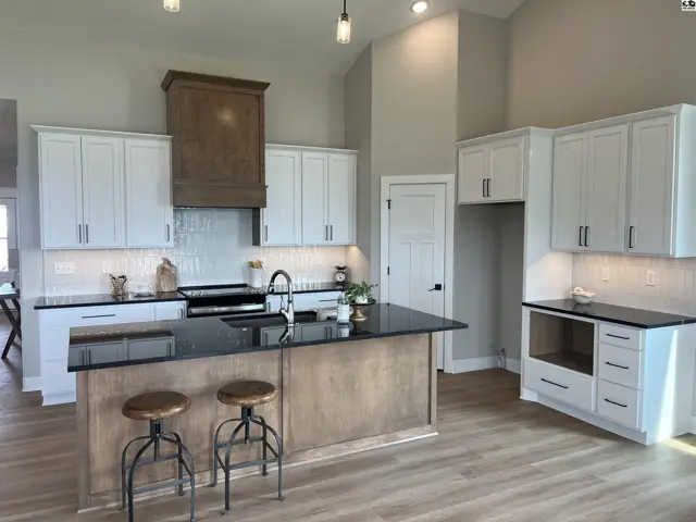Spacious kitchen with white cabinets, granite countertops, and a wood-accent island with seating.