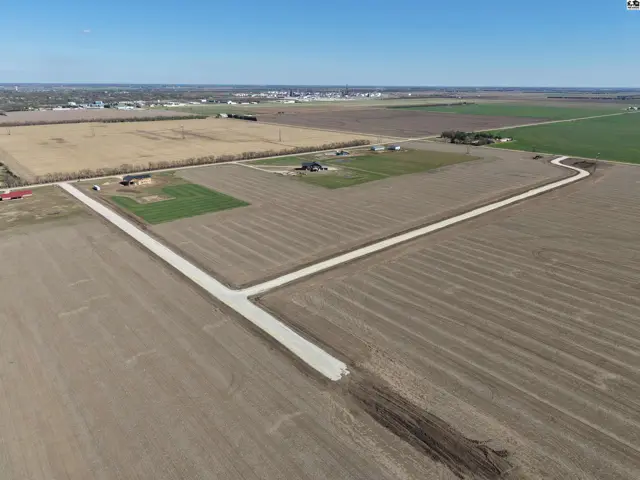 Aerial view of a rural property with a paved driveway winding through cultivated fields.