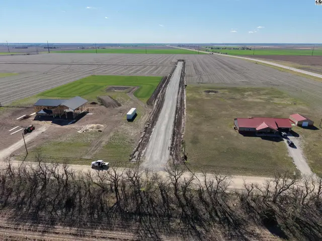 Aerial view of a rural property with two houses, a driveway, and surrounding agricultural fields.