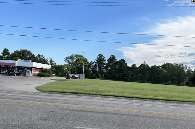 This property features a paved lot with a gas station and a large, open grassy area.