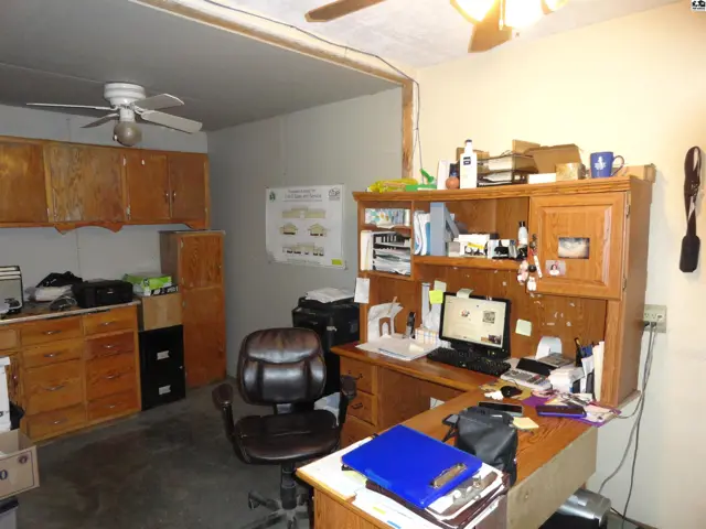 Spacious office with wooden cabinets, desk, computer, and ceiling fans.