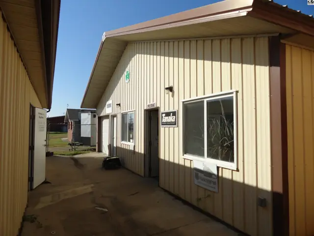 Tanaka building exterior with beige vertical siding, white-trimmed windows, and a brown overhang.