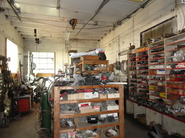 Spacious workshop with abundant shelving, tools, and natural light from large windows.