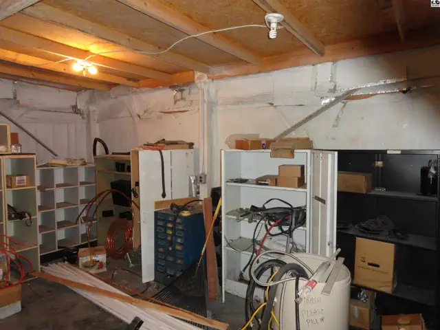 Unfinished basement with exposed wooden beams, concrete walls, and storage shelving.