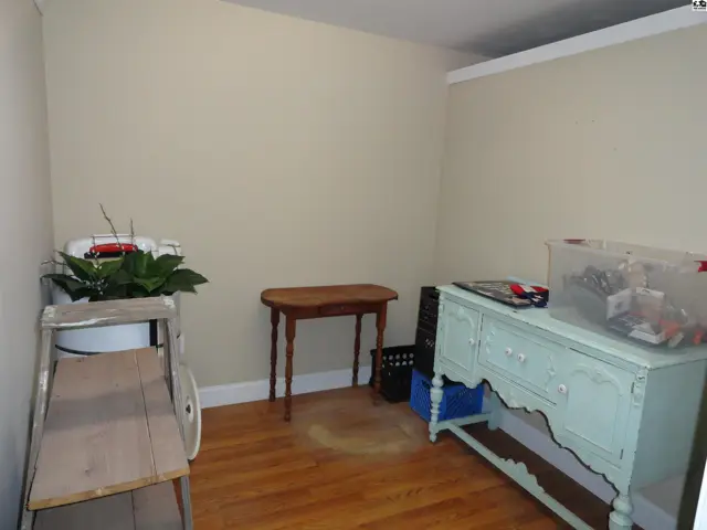 Light-filled room with hardwood floors, featuring a mint green dresser and a small wooden table.