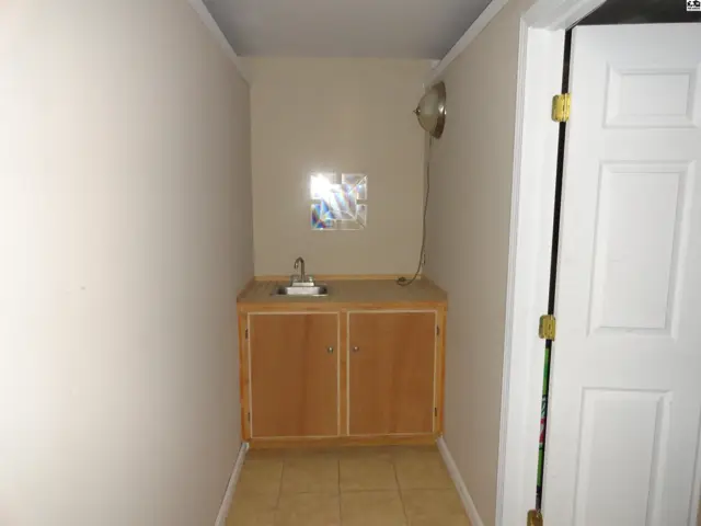 Small room with a light wood vanity, stainless steel sink, and tiled floor.