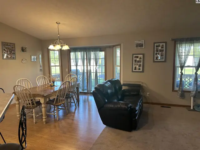 Open living and dining area with hardwood floors and carpeted seating space.