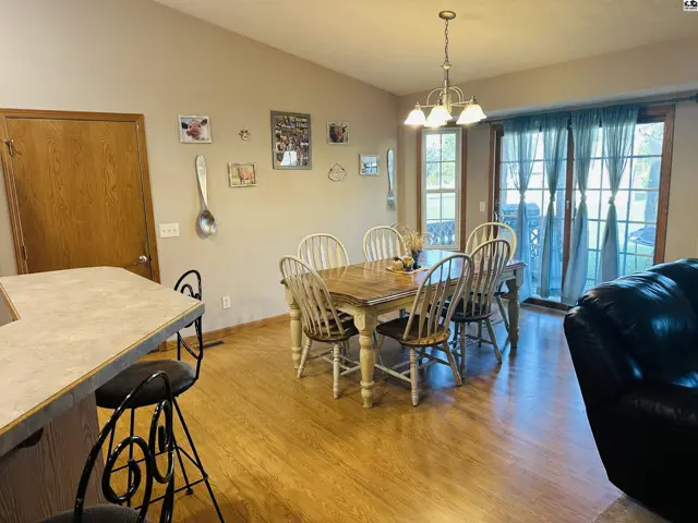 Dining area with wood table, chairs, and sliding glass doors.