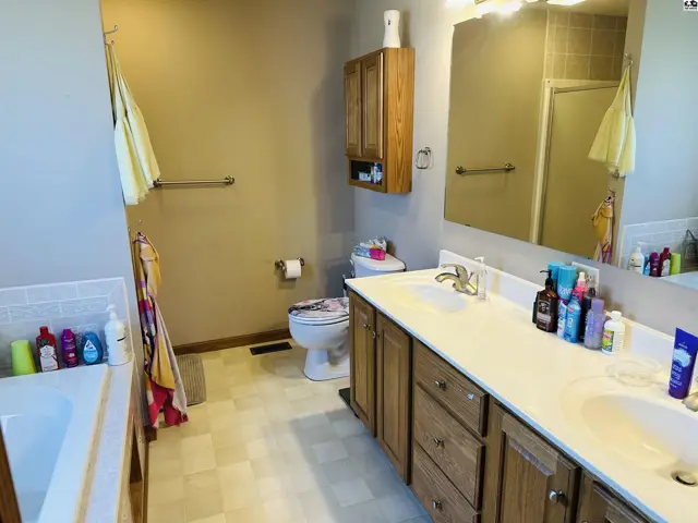 This bathroom features a double vanity, a bathtub, and a toilet.