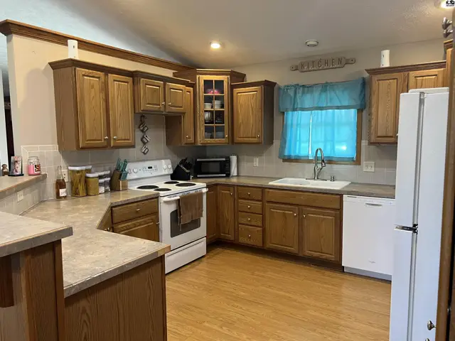This kitchen features light wood cabinetry, white appliances, and laminate countertops.