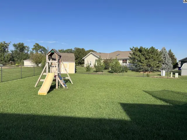 A fenced yard features a playset and a small yellow shed.
