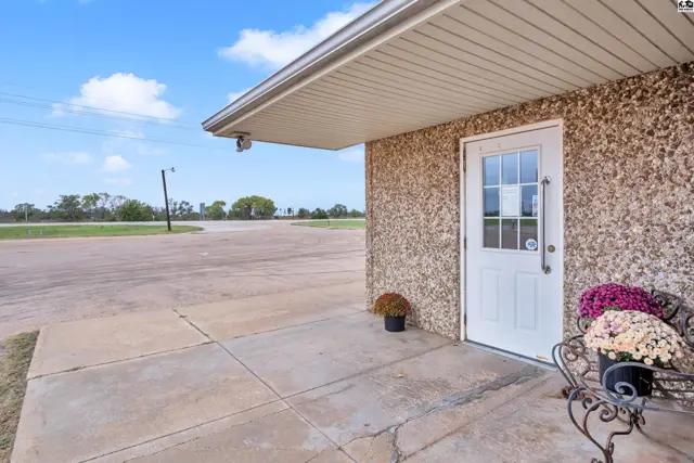 Exterior entrance with a white door, textured walls, and decorative planters.