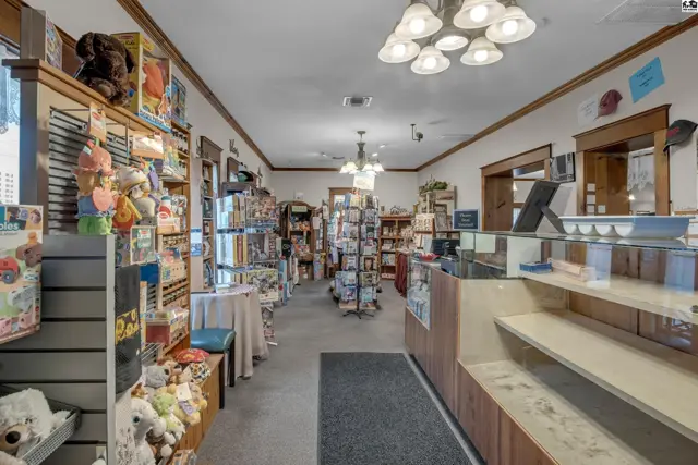 Retail store interior with wooden shelves, display cases, and merchandise including toys and cards.