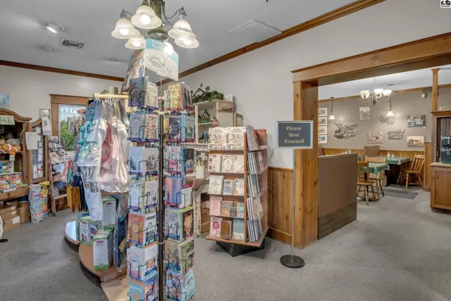 Interior view of a retail space with card displays, wooden accents, and a dining area beyond.