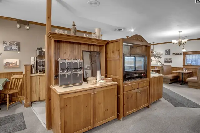 Warm wood cabinetry and counters showcase a coffee station and display cases in this dining area.