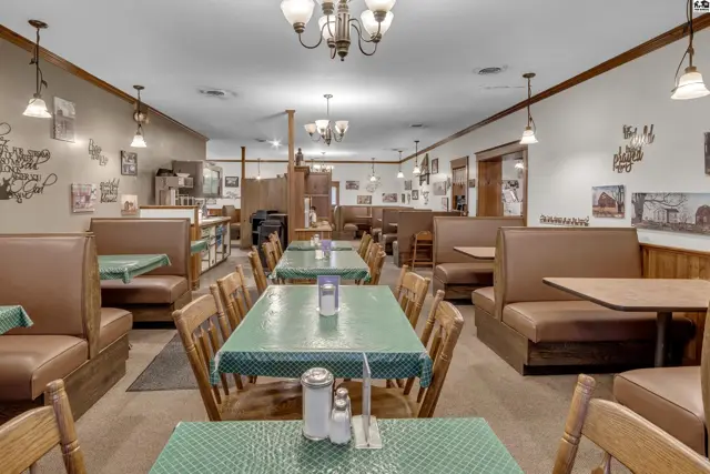 Spacious dining room with brown leather booths, green checkered tablecloths, and rustic wall decor.