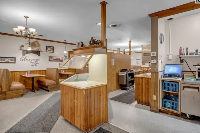 Cozy dining area with booth seating, wood paneling, and a service counter with a computer.