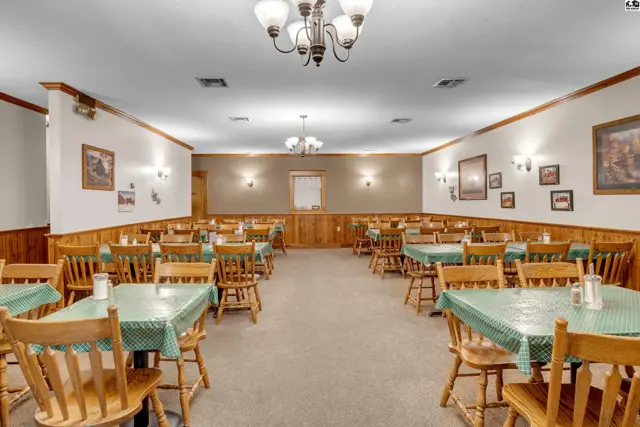 Spacious dining room with wood-paneled walls, checkered tablecloths, and ample seating.
