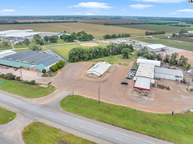 Aerial view of a commercial property with greenhouses, office buildings, and a gas station.