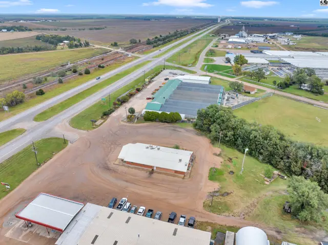 Aerial view of a commercial property with greenhouses, a main building, and adjacent highway access.