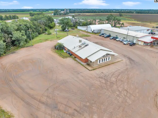 Commercial building with brick facade and metal roof, surrounded by a large gravel lot.