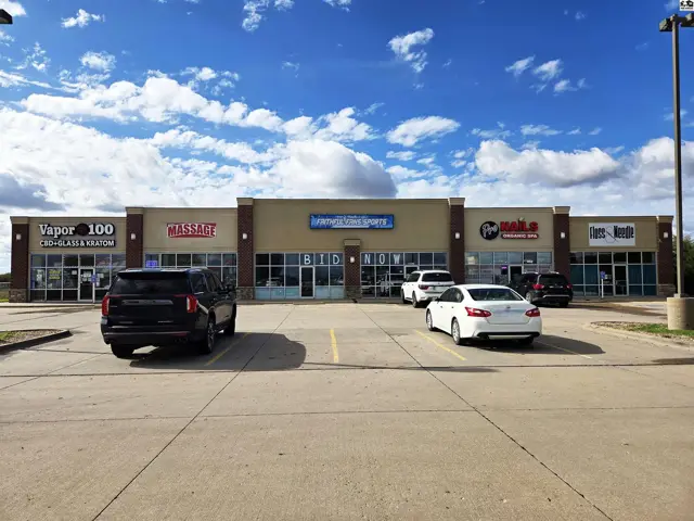 Modern commercial building exterior with multiple storefronts and a paved parking lot.