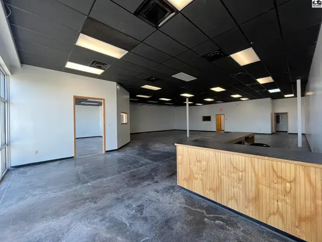 Spacious commercial interior with concrete floors, black ceiling, and a wood-paneled reception desk.