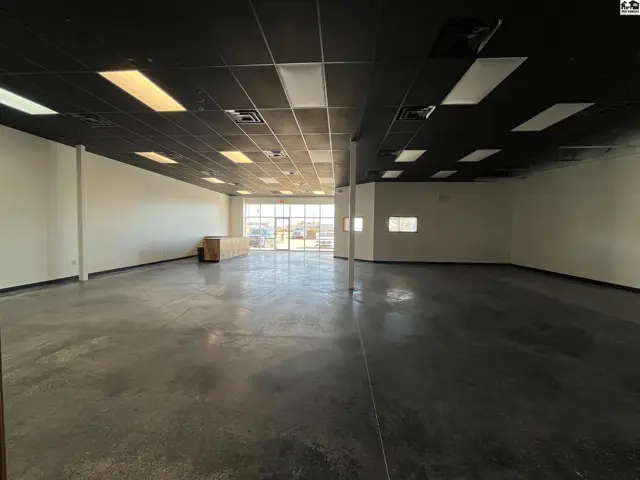 Spacious commercial interior with polished concrete floors, white walls, and a black drop ceiling.
