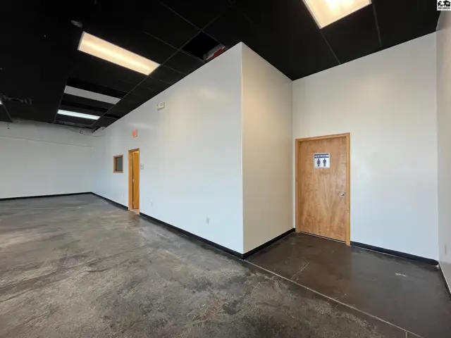 Spacious commercial interior with polished concrete floors, white walls, and a black drop ceiling.