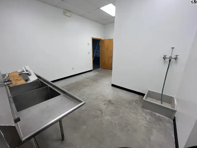 Commercial space with stainless steel sinks, concrete floors, and white walls.