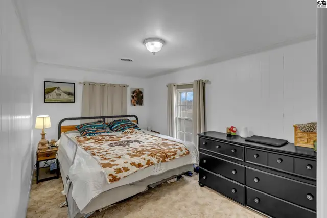 Spacious bedroom with a king-size bed, black dresser, and neutral carpet.