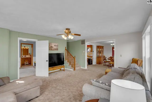 Spacious living room with plush carpet, sectional sofa, and view into a bathroom and dining area.