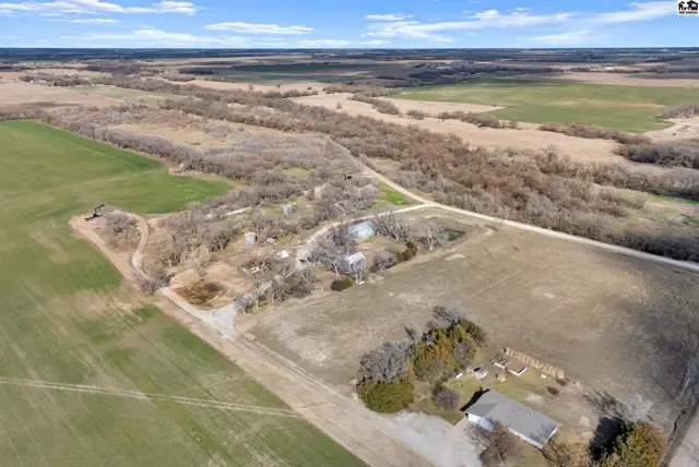 Aerial view of a rural property with scattered buildings, trees, and surrounding agricultural fields.