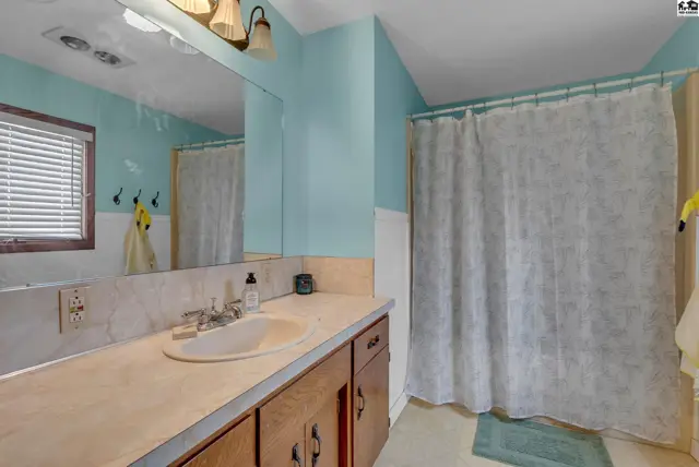 Bright bathroom with a light blue vanity, white tiled walls, and a wooden vanity.