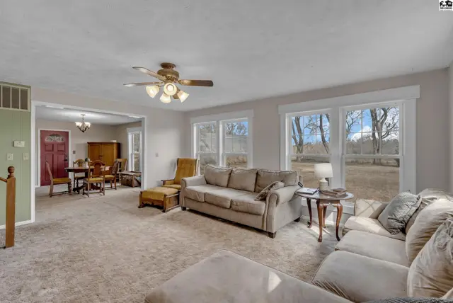 Spacious living room with neutral carpet, large windows, and a view of the outdoors.