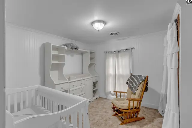 Bright nursery with white crib, changing station, rocking chair, and neutral carpet.