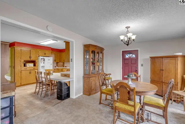 Spacious dining area with a wooden hutch and table, adjacent to a kitchen with oak cabinets.