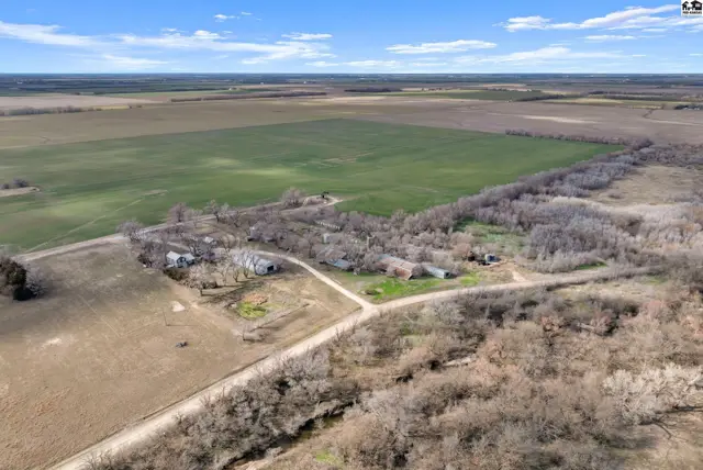 Aerial view of a rural property with farm buildings nestled among trees, surrounded by fields.
