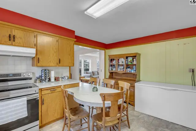 Bright kitchen with oak cabinets, white countertops, and a dining set next to a hutch.