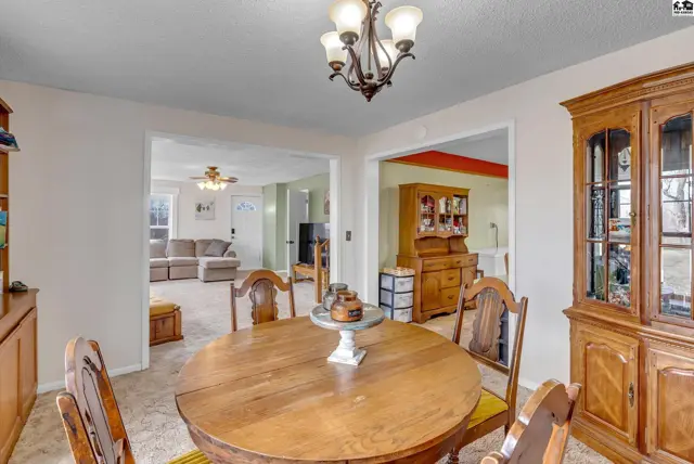 Dining room with a round wooden table, chairs, and a large wooden hutch.