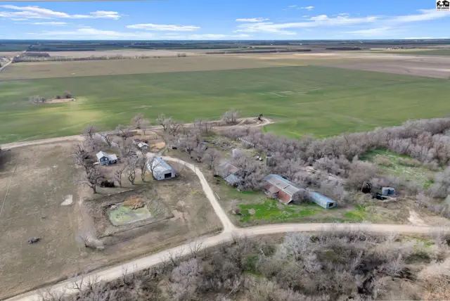Aerial view of a rural property with farm buildings, a pond, and surrounding agricultural fields.