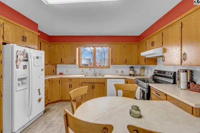 Spacious kitchen with light oak cabinets, white appliances, and a round breakfast table.