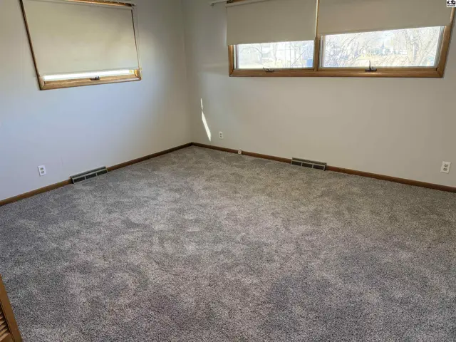 Carpeted room with two windows, baseboard heating, and neutral walls.