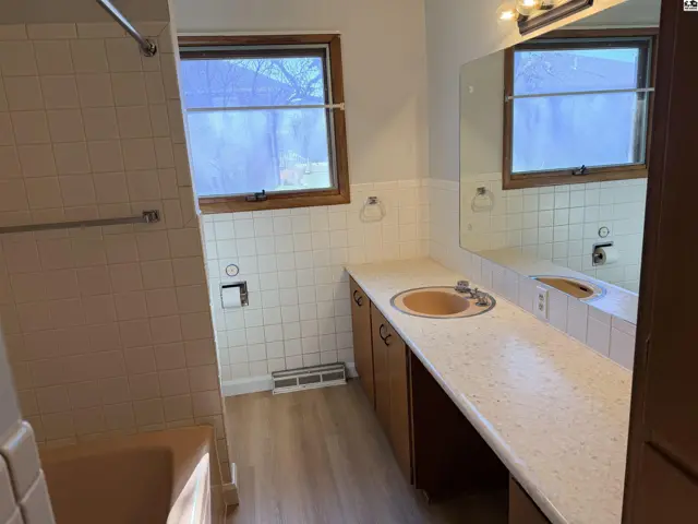 This bathroom features a long vanity with a speckled countertop and a built-in sink.